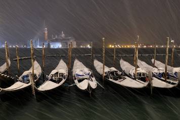 Gondolas are seen during snowfall in the Venice lagoon