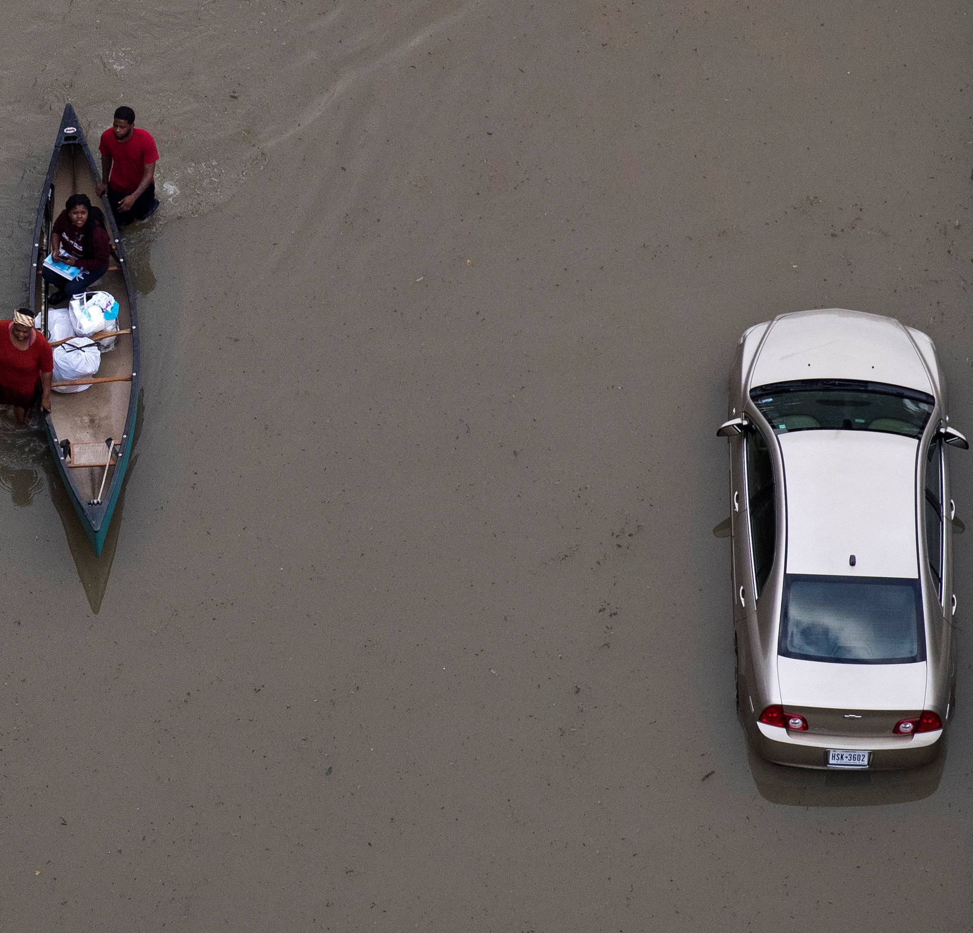 Residents hold on to a canoe as they navigate through flood waters brought by Tropical Storm Harvey in Northwest Houston