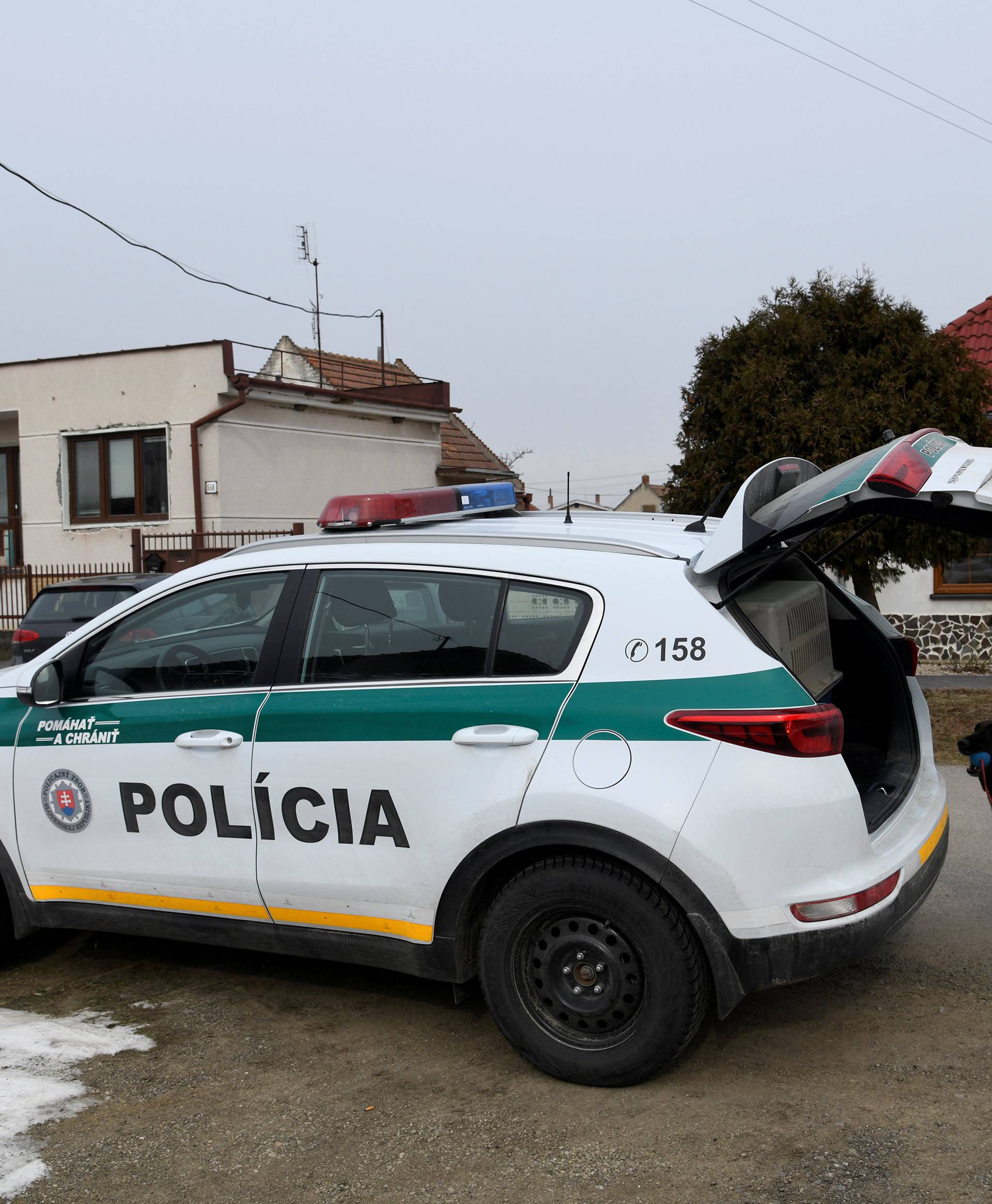 A police officer with a dog is seen near a house where Slovak investigative journalist Jan Kuciak and his girlfriend Martina Kusnirova lived and were murdered in the village of Velka Maca