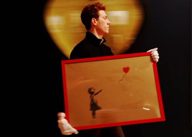 FILE PHOTO: An employee walks with artist Banksy