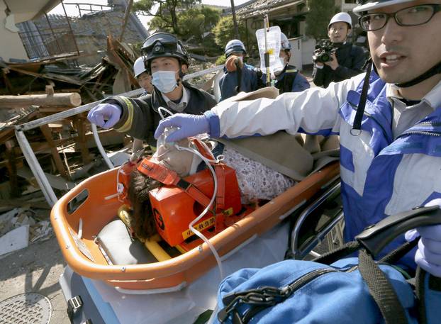 A woman is carried away by rescue workers after being rescued from her collapsed home caused by an earthquake in Mashiki town, Kumamoto prefecture, southern Japan