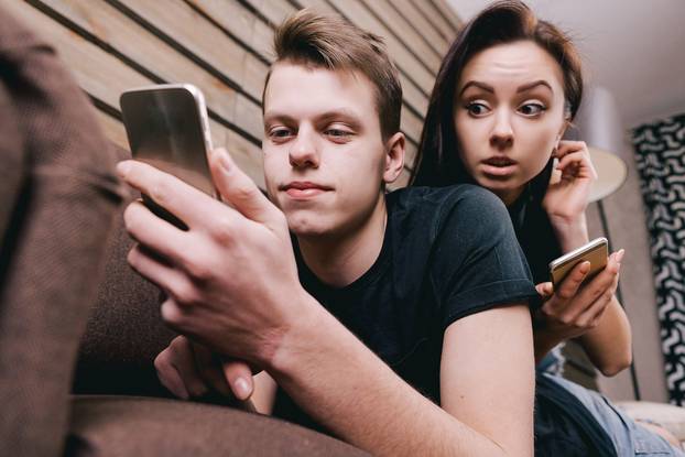 cute couple in bed with digital phone in hands