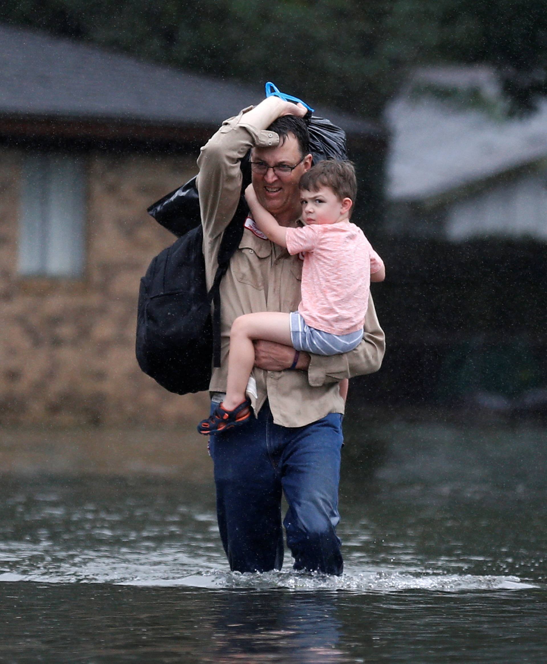 David Michaelis holds his 3-year-old grandson Teddy as he wades through flood waters from Tropical Storm Harvey in Orange