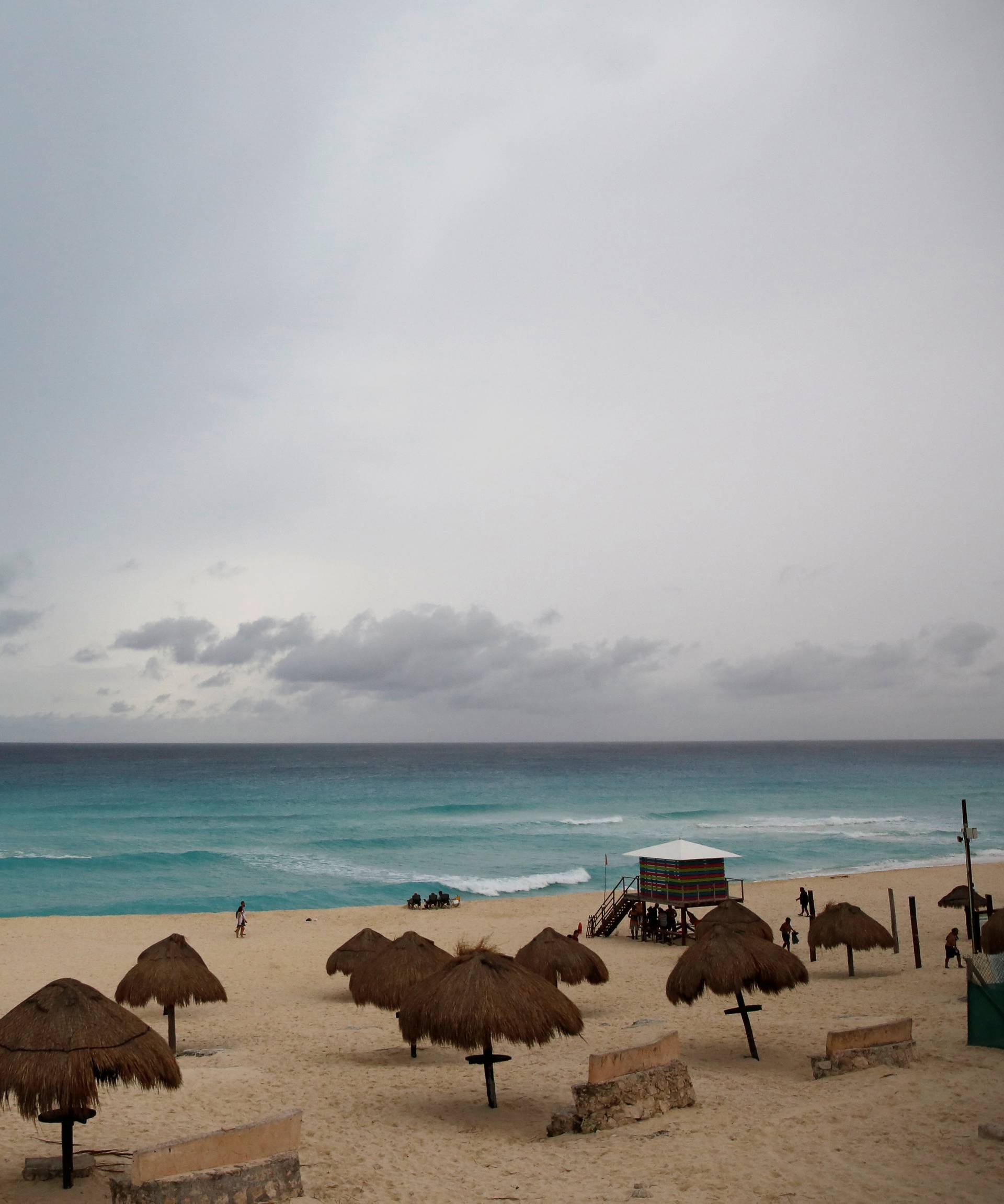Tourists walk at the beach as Tropical Storm Nate approaches in Cancun