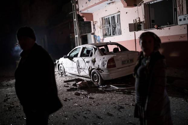 People stand in front of a building which was hit by rockets fired from Syria, in the Turkish border town of Kilis