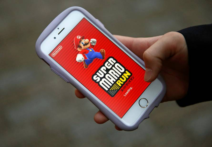 Takuya Nishya shows Nintendo's "Super Mario Run" game on his smartphone by the request of a photographer in Tokyo