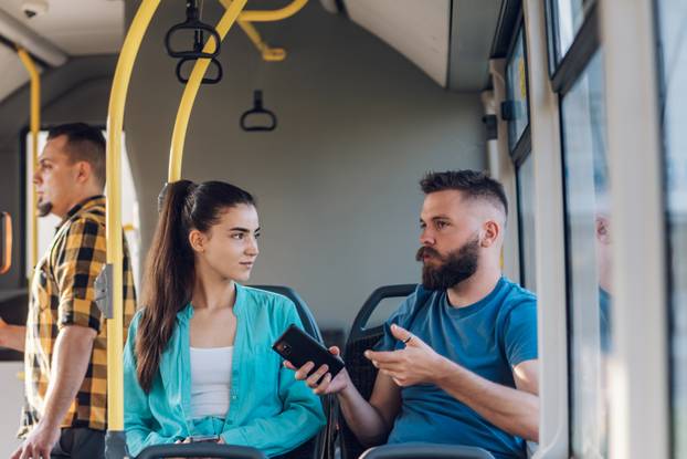 Young couple of friends talking while riding a bus in the city