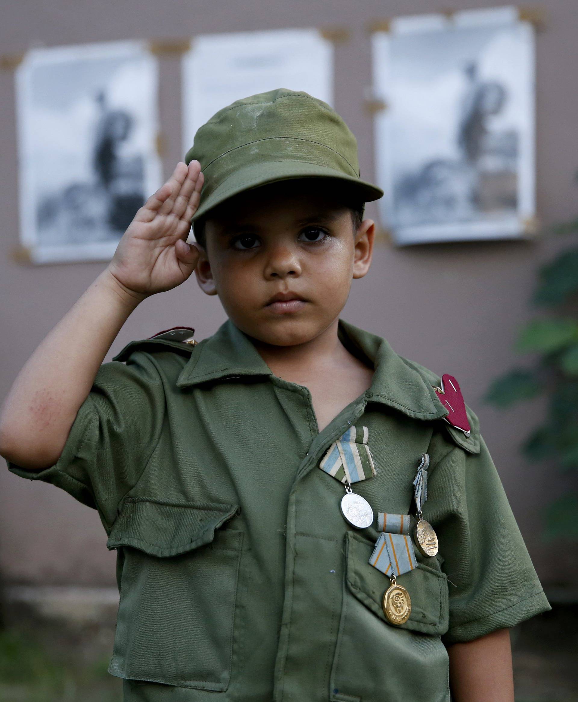 Child salutes while awaiting the caravan carrying Castro's ashes in Camaguey