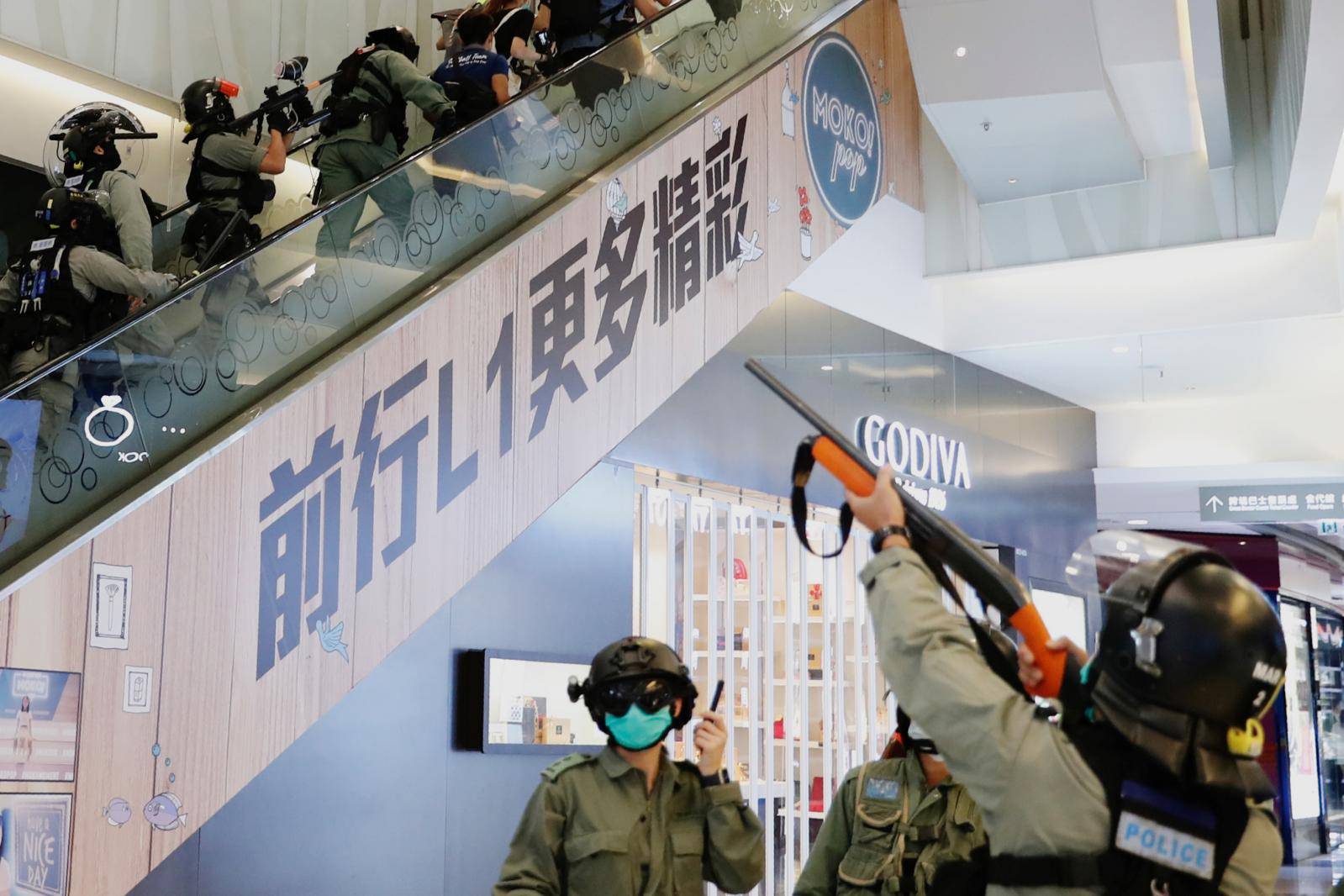 Riot police raise their pepper spray projectile inside a shopping mall as they disperse anti-government protesters during a rally, in Hong Kong