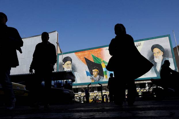 FILE PHOTO: People walk near a mural featuring images of Iran's Supreme Leader Ayatollah Ali Khamenei and leader of Iran's 1979 Islamic Revolution Ayatollah Ruhollah Khomeini, on a street in Tehran