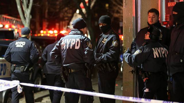 New York Police Department (NYPD) officers stand guard during an evacuation following a fire at an apartment building in New York