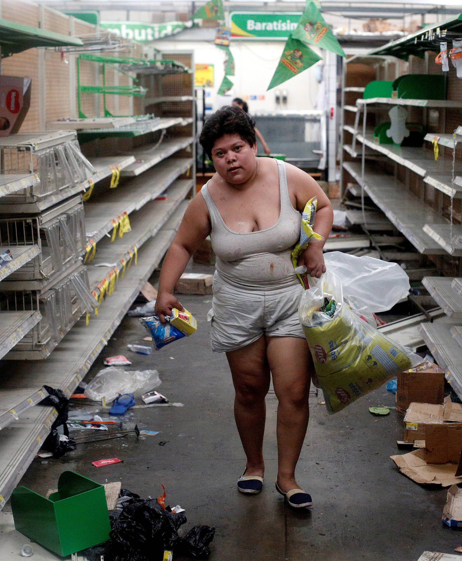 Woman with goods looted from a store is seen after protests in Managua