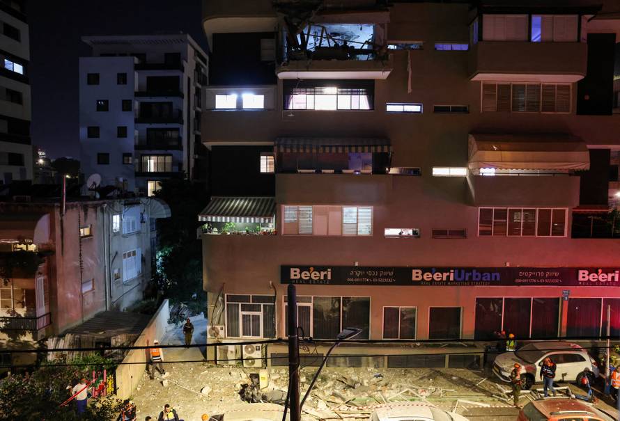 Emergency personnel inspect damage in a building following an Iranian projectile strike, amid the U.S.-Israeli conflict with Iran, in central Israel