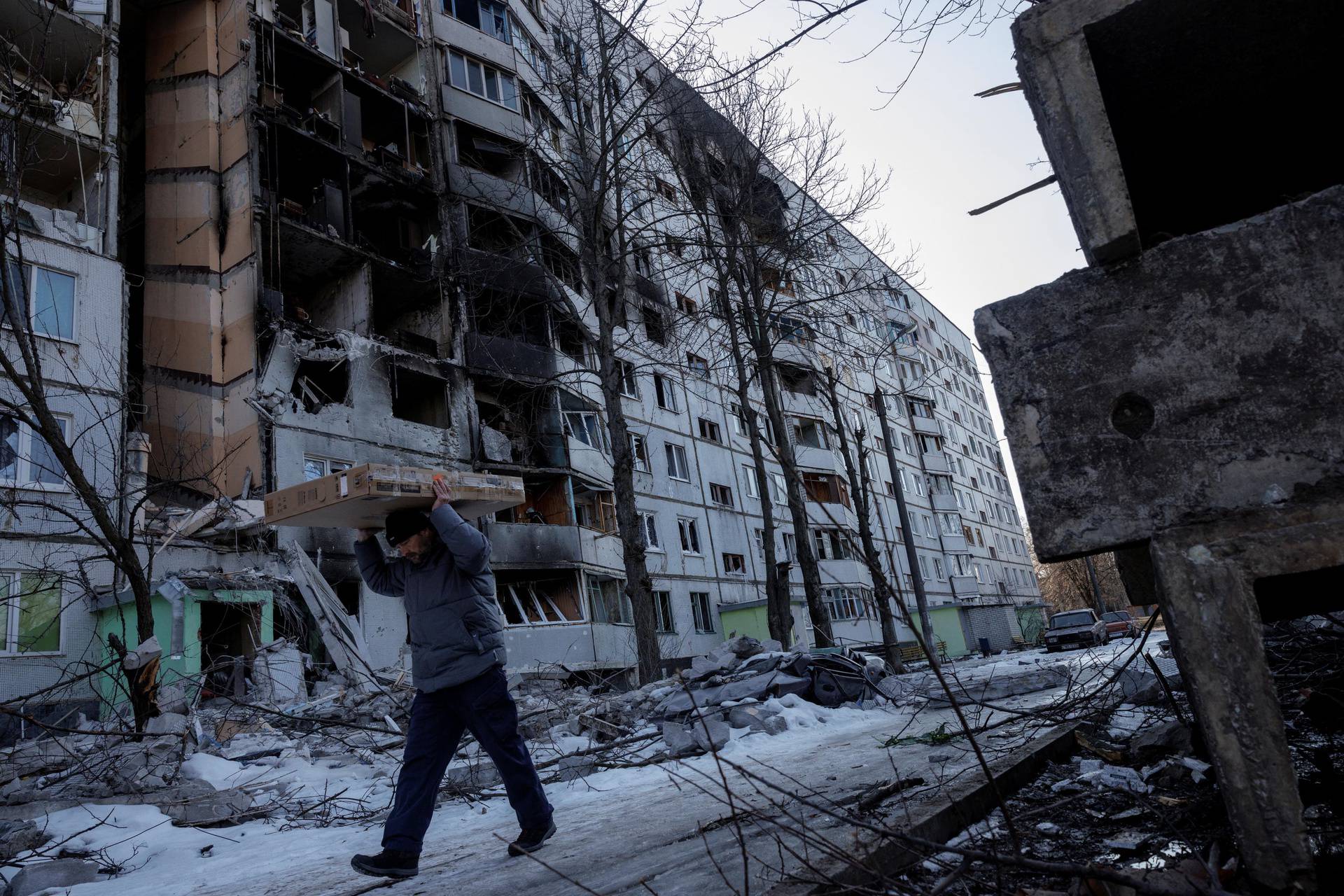 A man carries belonging out of a house that was hit by bombing in a northern district of Kharkiv as Russia's attack on Ukraine continues