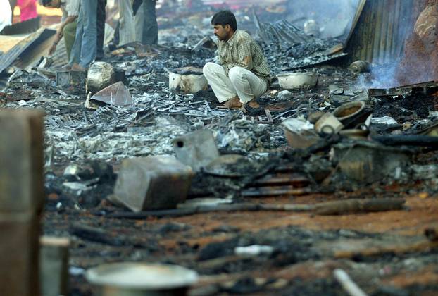 FILE PHOTO: A survivor sits among the debris of burnt shops near Mandherdevi temple in Wai village, southeast of Bombay, India