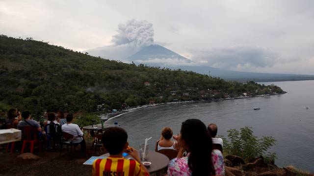 People watch Mount Agung volcano erupt from a cafe near Amed, Karangasem Regency, Bali