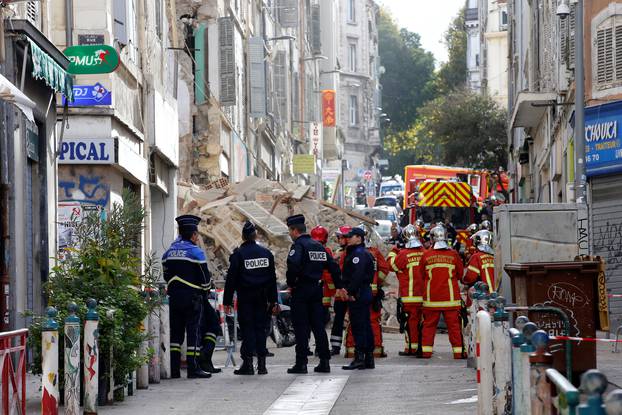 French police and rescue workers are seen near rubble after buildings collapsed in central Marseille