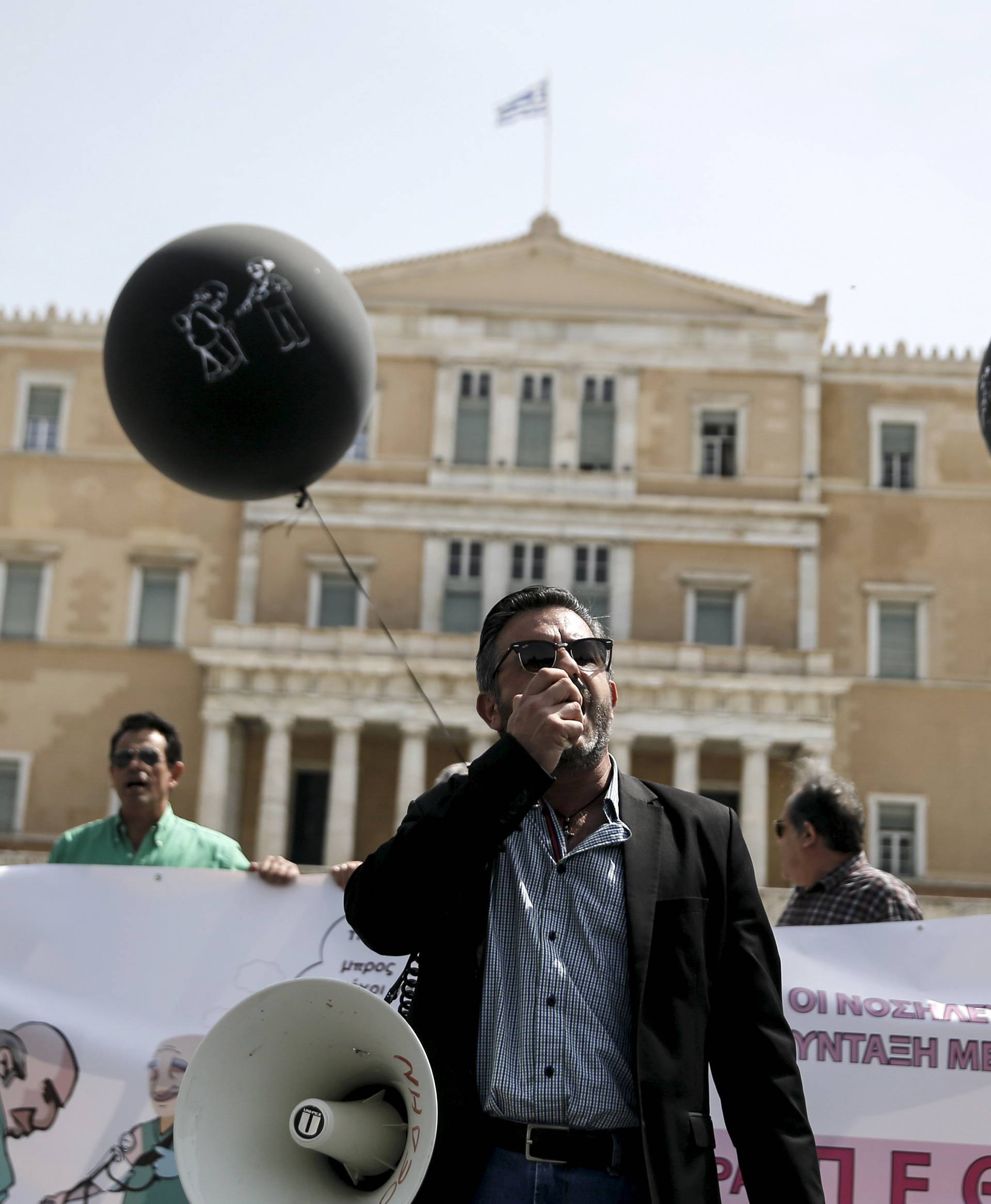 A protester shouts slogans through a loudspeaker in front of the parliament building, during a demonstration marking a 24-hour strike of the country's biggest public sector union ADEDY against planned tax and pension reforms in Athens