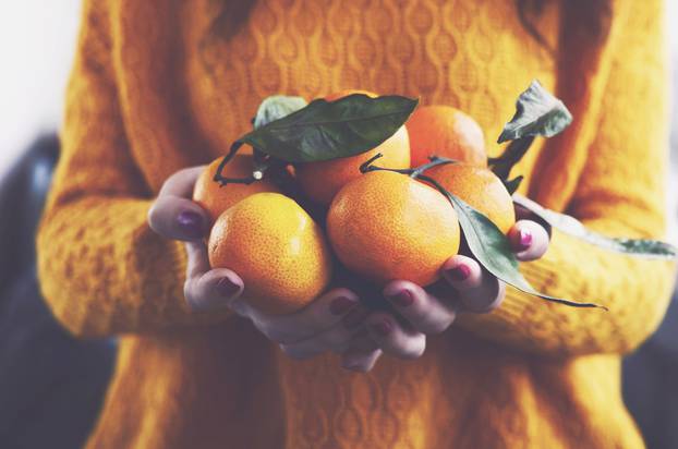 Woman,In,Yellow,Knitted,Pullover,With,Ripe,Clementines,In,Her
