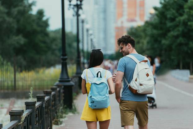 back view of man and woman with backpacks talking outside 