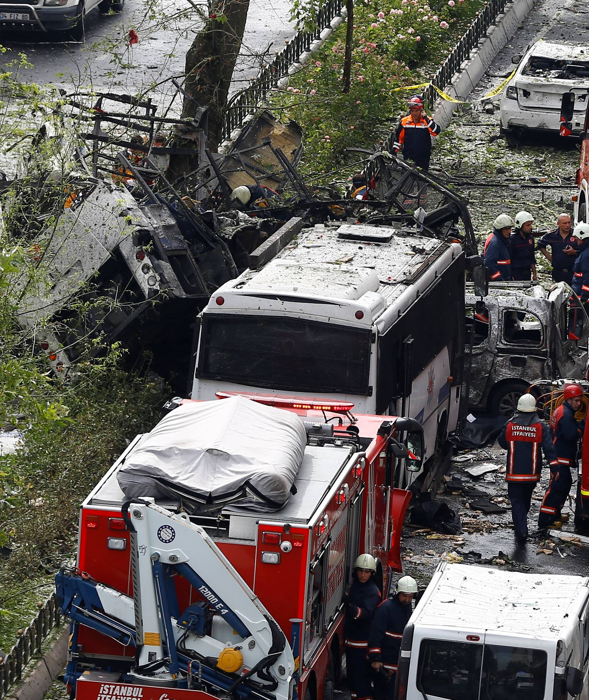 Forensic experts and firefighters stand beside a Turkish police bus which was targeted in a bomb attack in Istanbul