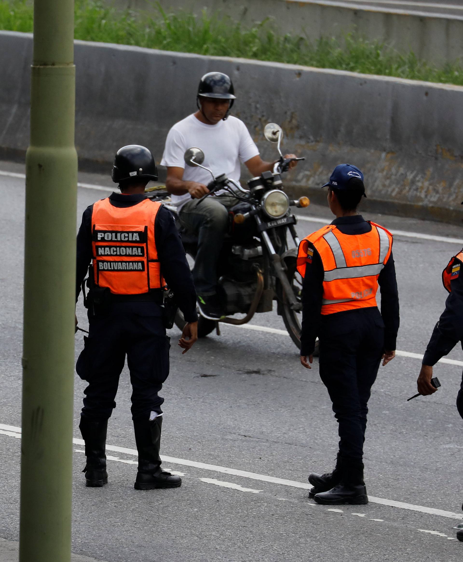 Police officers stand guard at a checkpoint during a shootout between security forces and rogue Venezuelan helicopter pilot Oscar Perez, in Caracas