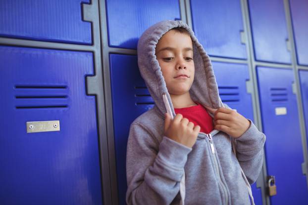 Boy wearing hooded shirt by lockers