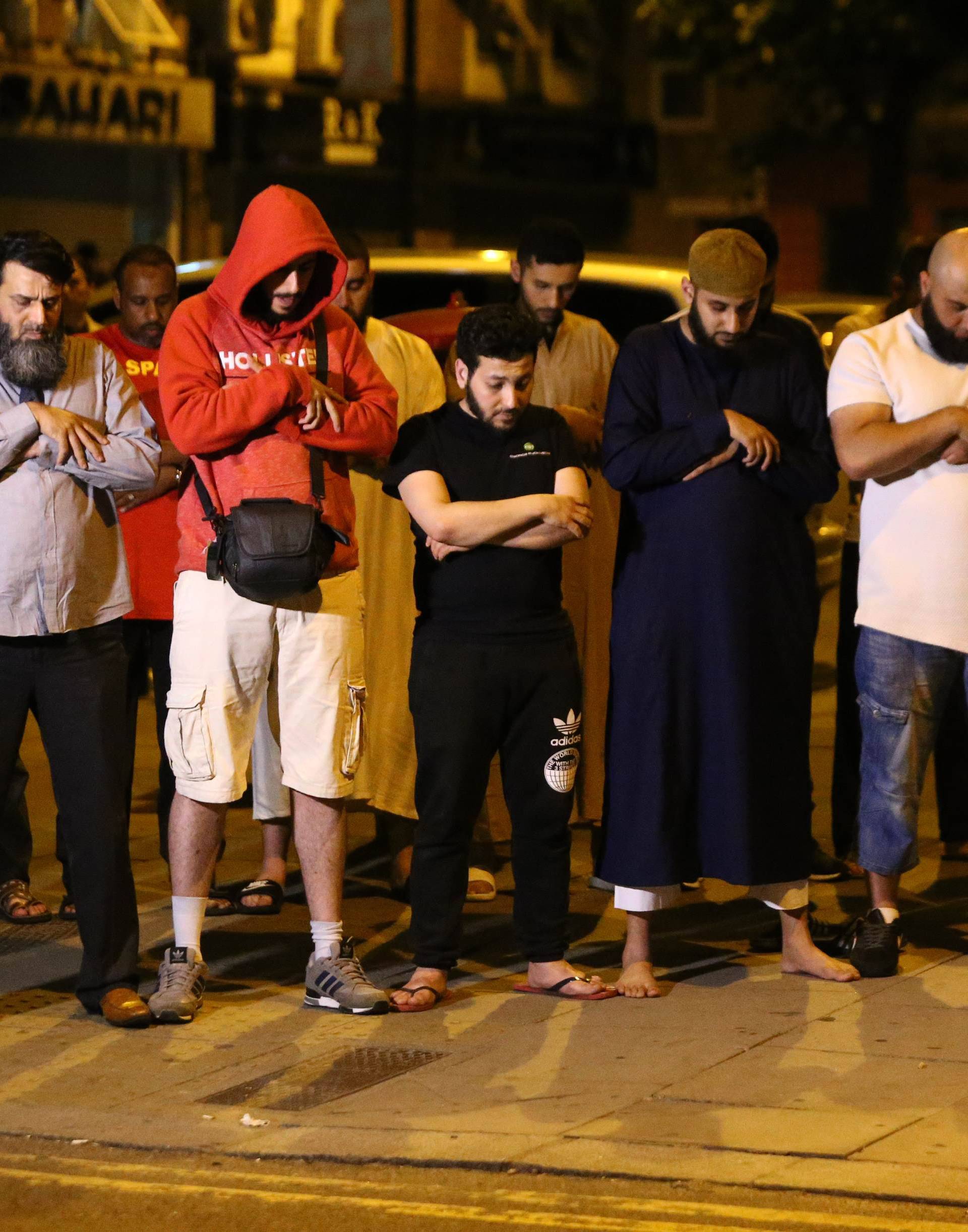 Men pray after a vehicle collided with pedestrians near a mosque in the Finsbury Park neighborhood of North London