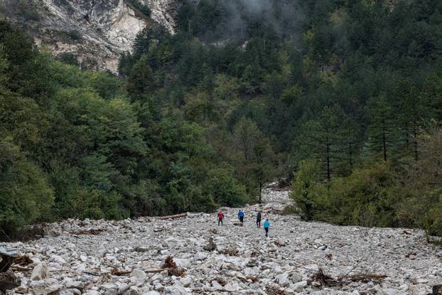 Rescue workers walk among debris following a landslide in the flooded village of Donja Jablanica