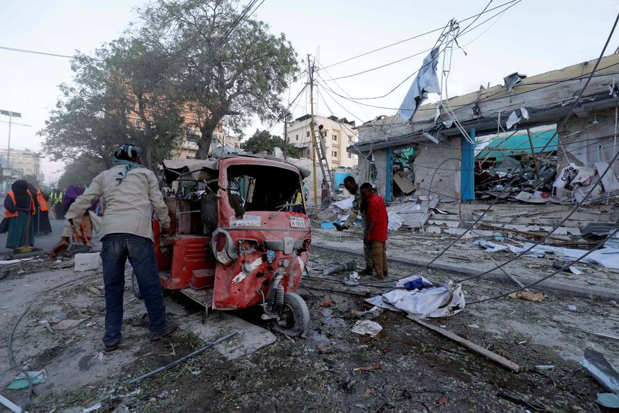 People watch the rubble near damaged buildings after a suicide car bomb exploded, targeting a hotel in a business center in Maka Al Mukaram street, Mogadishu