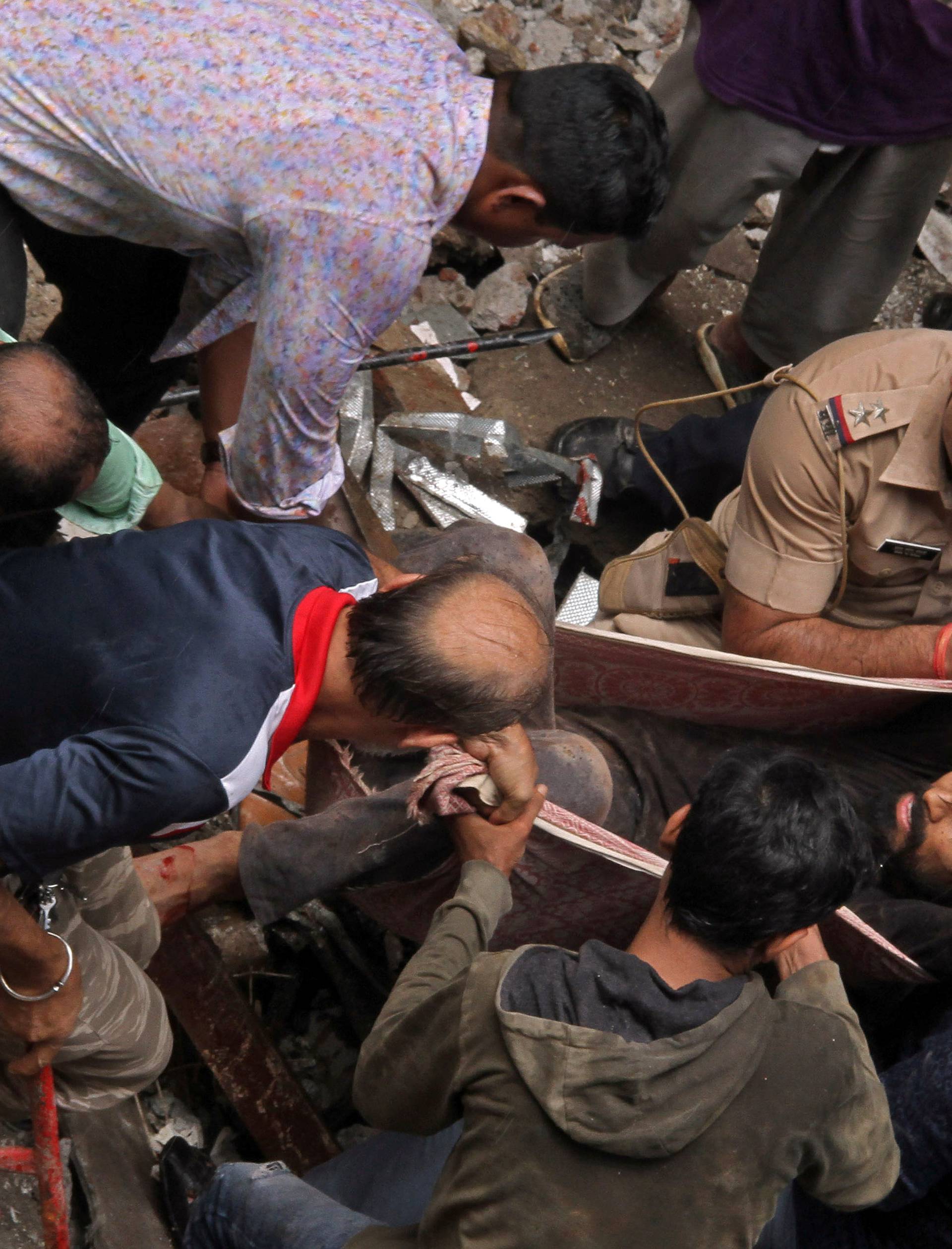 Rescue workers carry a man who was rescued from the rubble at the site of a collapsed building in Mumbai