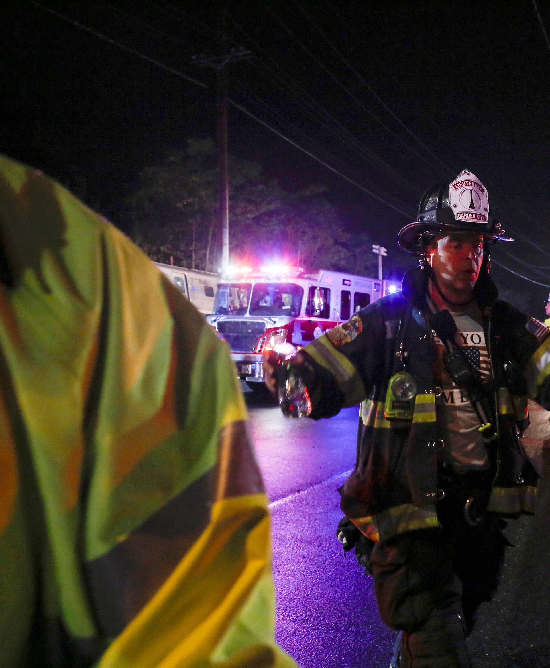 A firefighter clears the area while emergency responders  attend to a train that sits derailed near the community of New Hyde Park on Long Island in New York