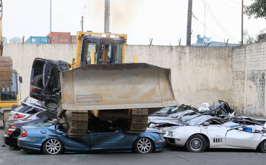 A bulldozer destroys condemned smuggled luxury cars worth 61,626,000.00 pesos during the 116th Bureau of Customs founding anniversary in Manila