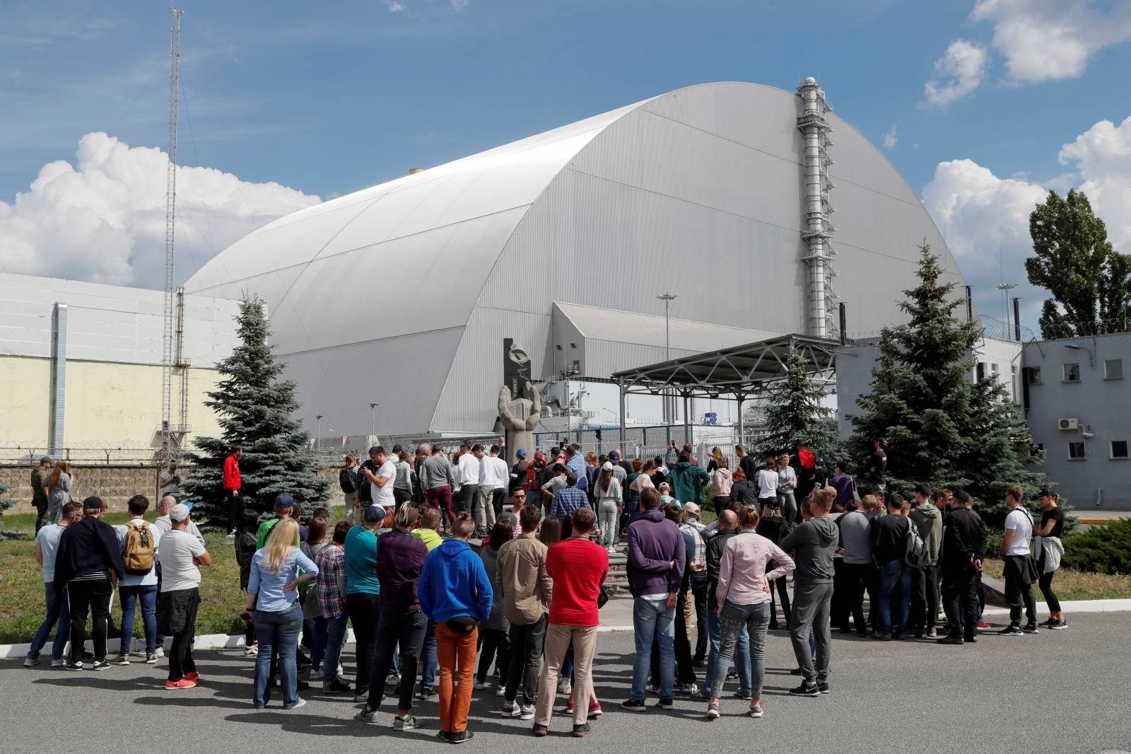 Visitors stand outside the New Safe Confinement (NSC) structure over the old sarcophagus covering the damaged fourth reactor at the Chernobyl Nuclear Power Plant, in Chernobyl