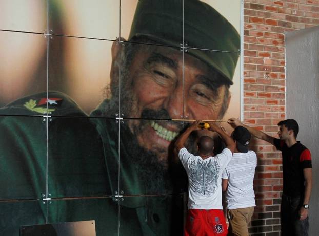 Workers install a photograph of Cuba