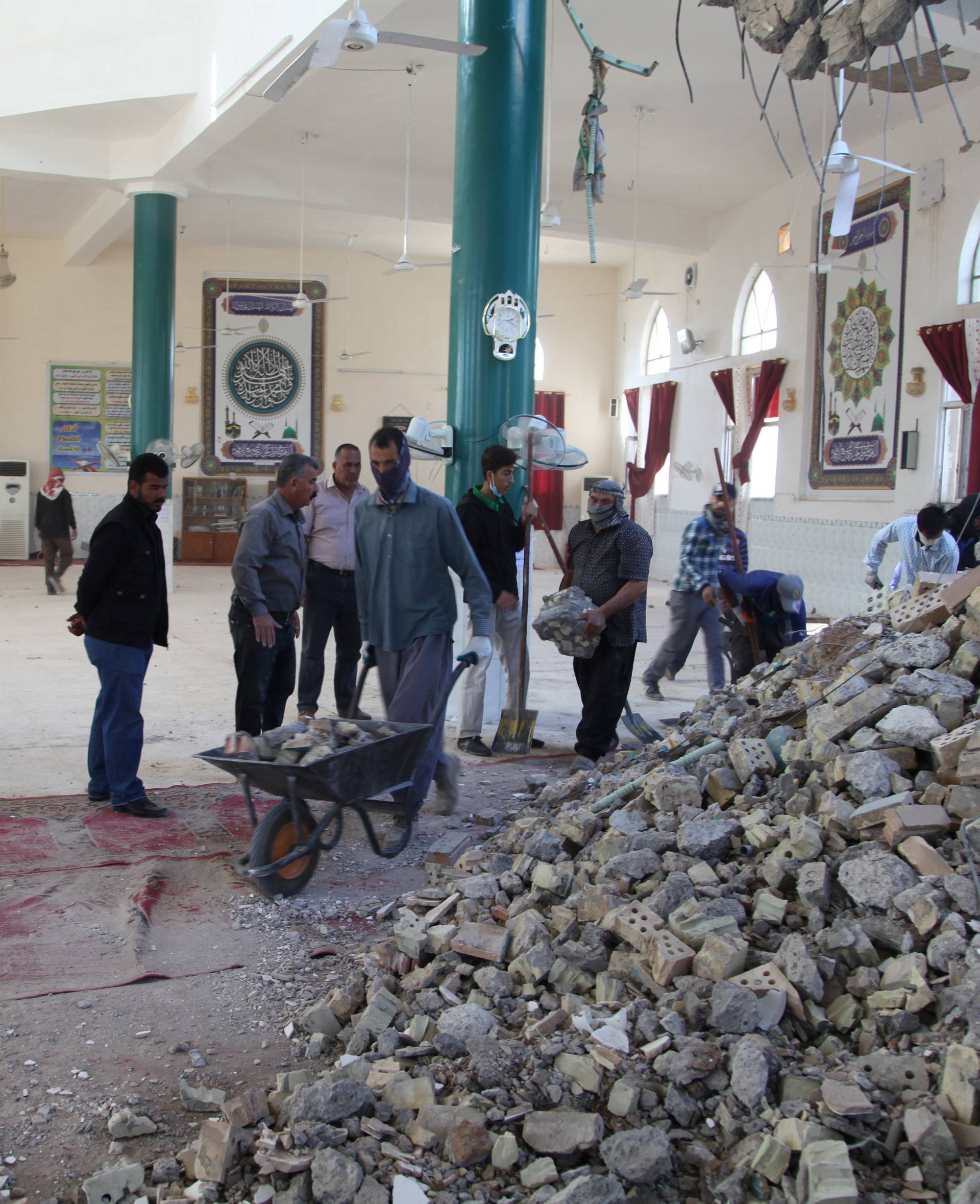 People remove rubble from a damaged mosque following an earthquake in Khanaqin