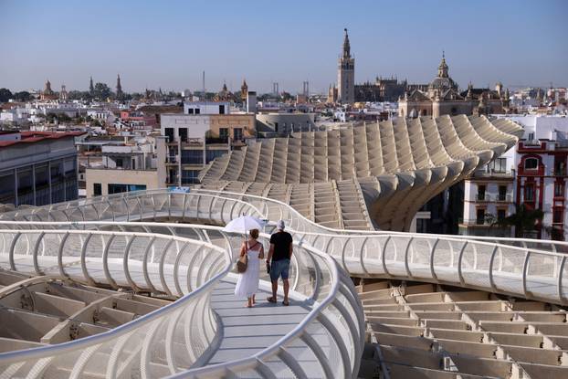 A tourist walks with an umbrella on Las Setas, during a heatwave , in Seville