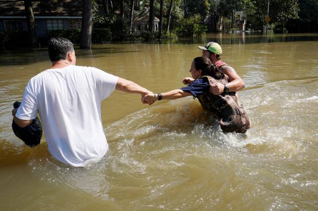 Melissa Ramirez struggles against the current flowing down a flooded street helped by Edward Ramirez and Cody Collinsworth as she tried to return to her home for the first time since Harvey floodwaters arrived in Houston