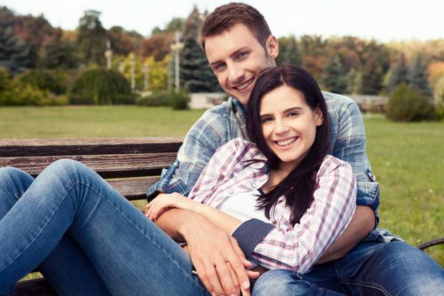 Couple relaxing on bench in front of skyline summer time.