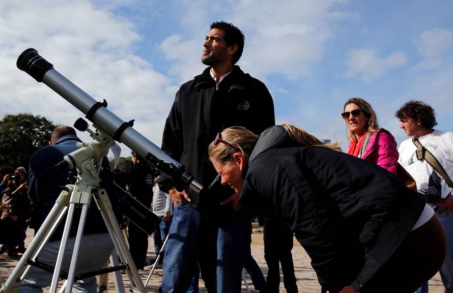 A woman uses a telescope to observe the planet Mercury transit in front of the sun outside Buenos Aires' planetarium
