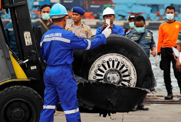 A worker assists his colleague during the lift up of a damaged tyre from the Lion Air flight JT610 jet, at Tanjung Priok port in Jakarta