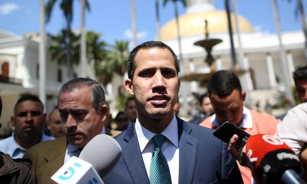 Venezuelan opposition leader Juan Guaido walks as he speaks to journalists before a news conference at the National Assembly in Caracas