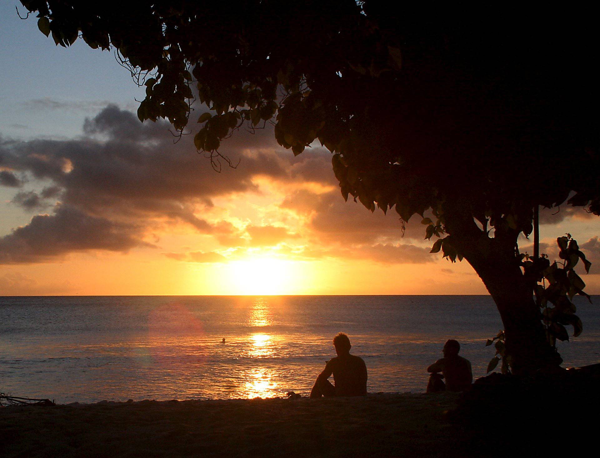 Surfers watch the sun set after surfing along the coast of Kiritimati Island, part of the Pacific Island nation of Kiribati