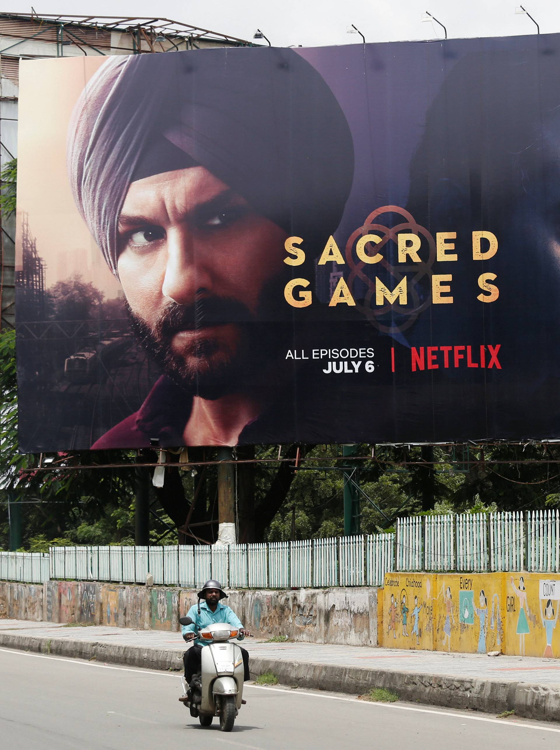 A man rides his scooter past a hoardings of Netflix's new television series "Sacred Games" in Bengaluru,