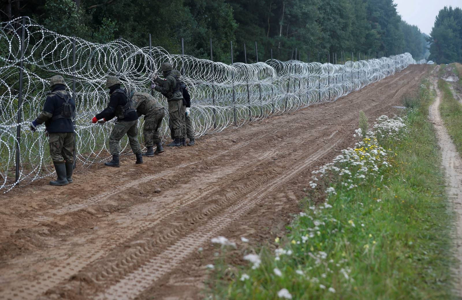 FILE PHOTO: Polish soldiers build a fence on the border between Poland and Belarus near the village of Nomiki