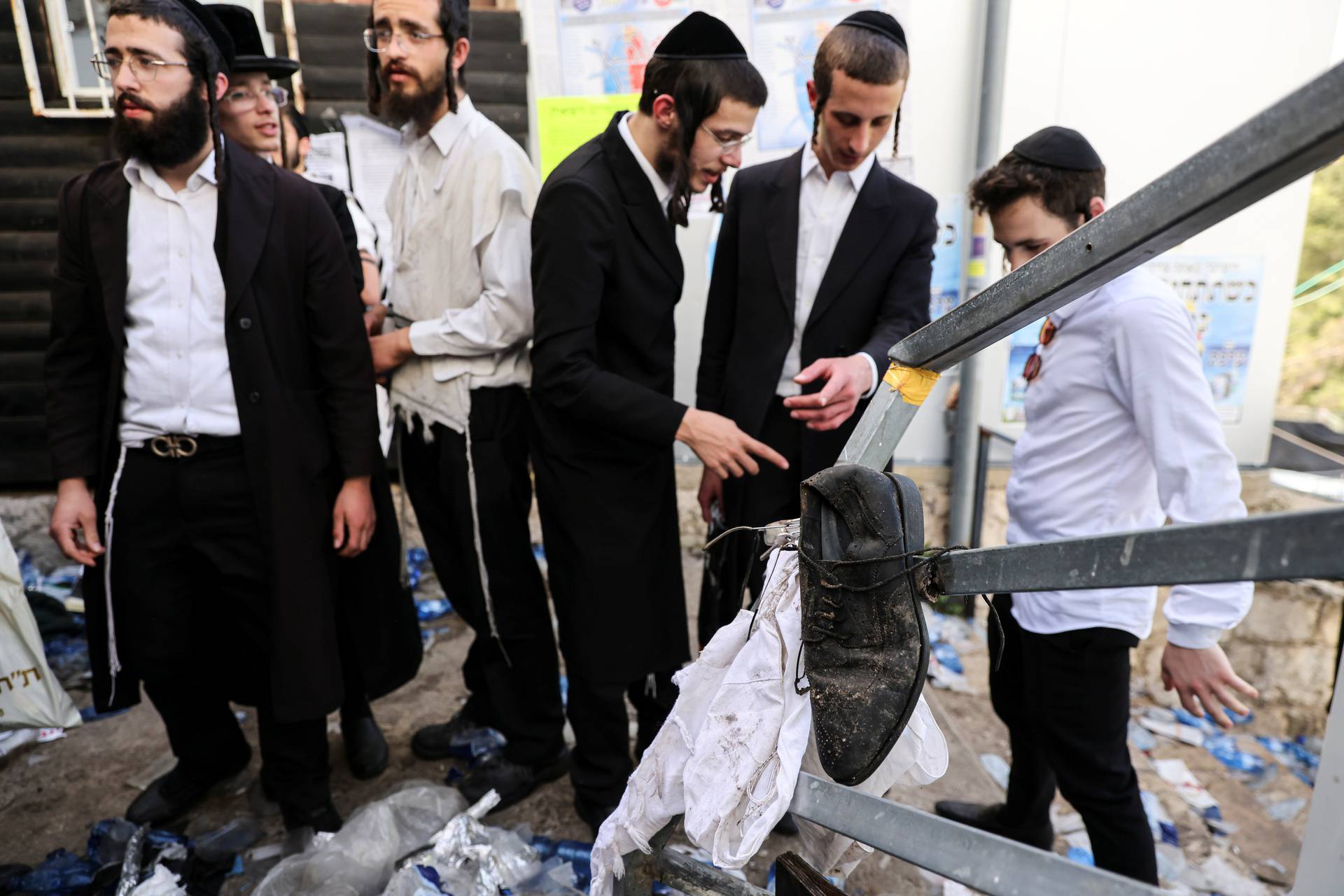 Ultra Orthodox Jews stand next to left over belongings on Mount Meron