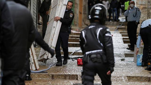 An Israeli policeman carries a privacy partition near the site of a shooting incident in Jerusalem's Old City