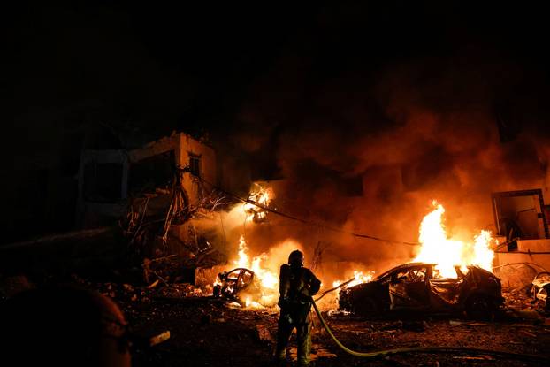 An Israeli firefighter works to put out a fire on a car at the site of a projectile impact after Iran launched missiles into Israel, following Israeli and U.S. strikes on Iran, in Tel Aviv