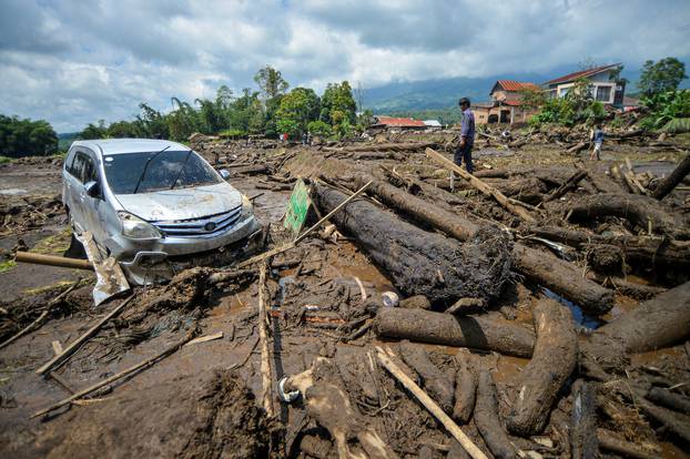 A man stands near a damaged car in an area affected by heavy rain brought flash floods and landslides in Agam