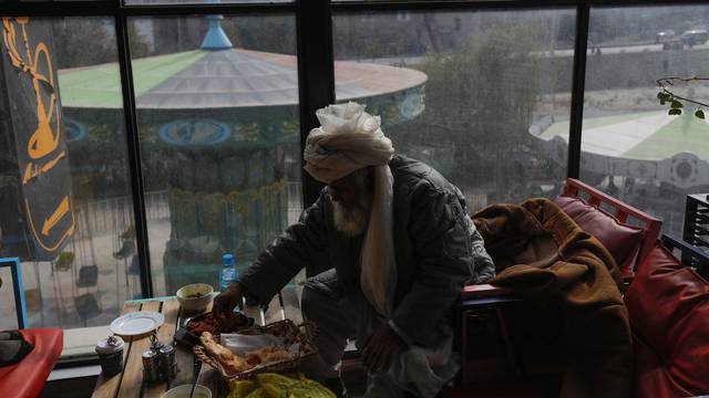 A Taliban member eats food in a restaurant in an amusement park in Kabul